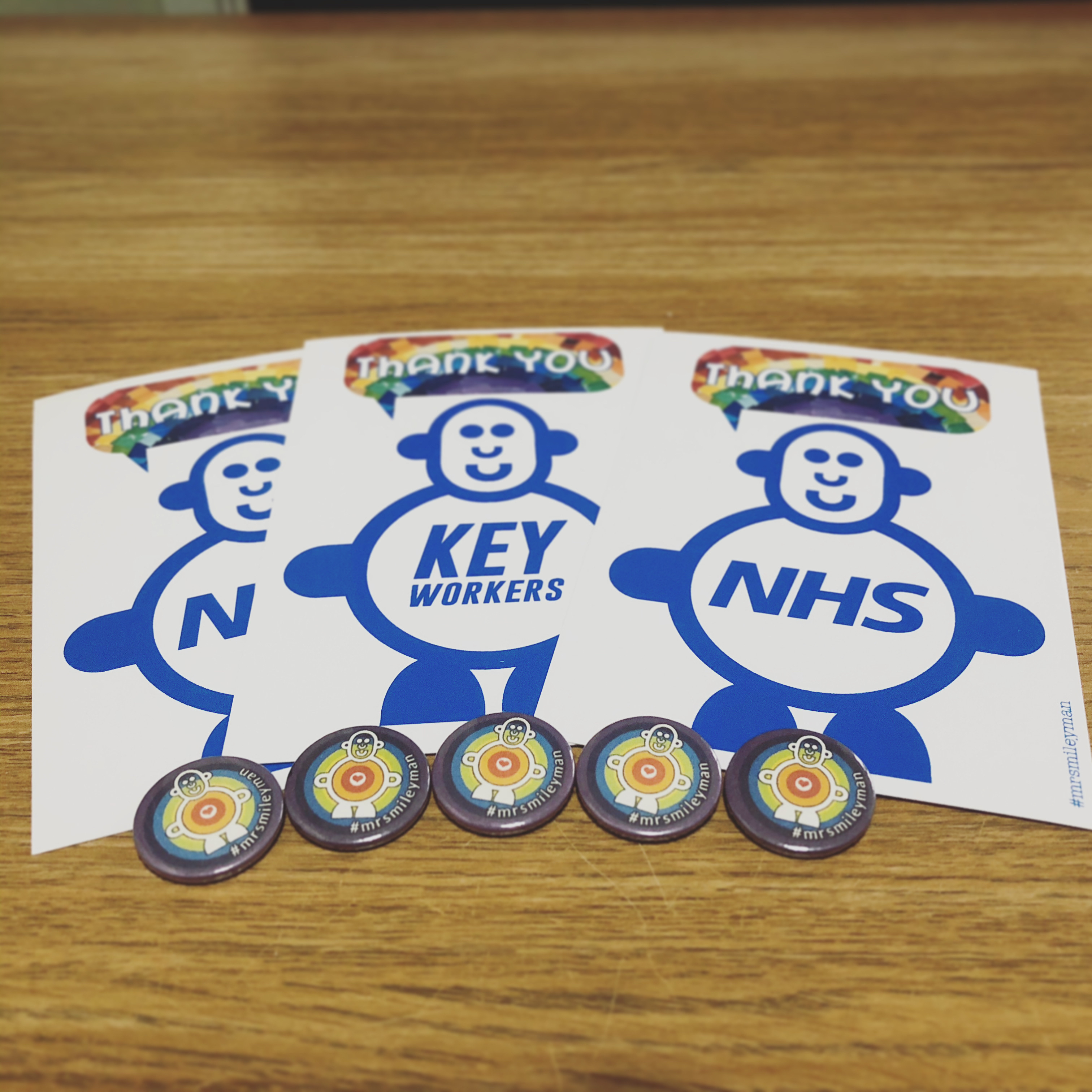 Postcards and pin badges displaying cute smileyman character and thank you message